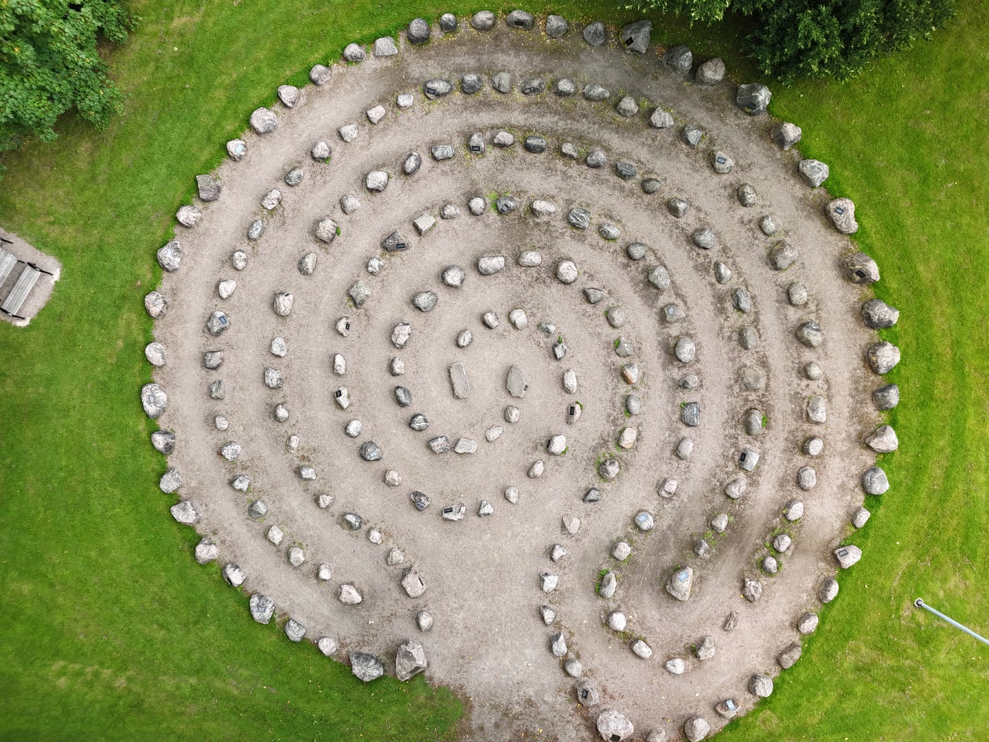 A large spiral of stones set in grass and gravel, photographed from above.