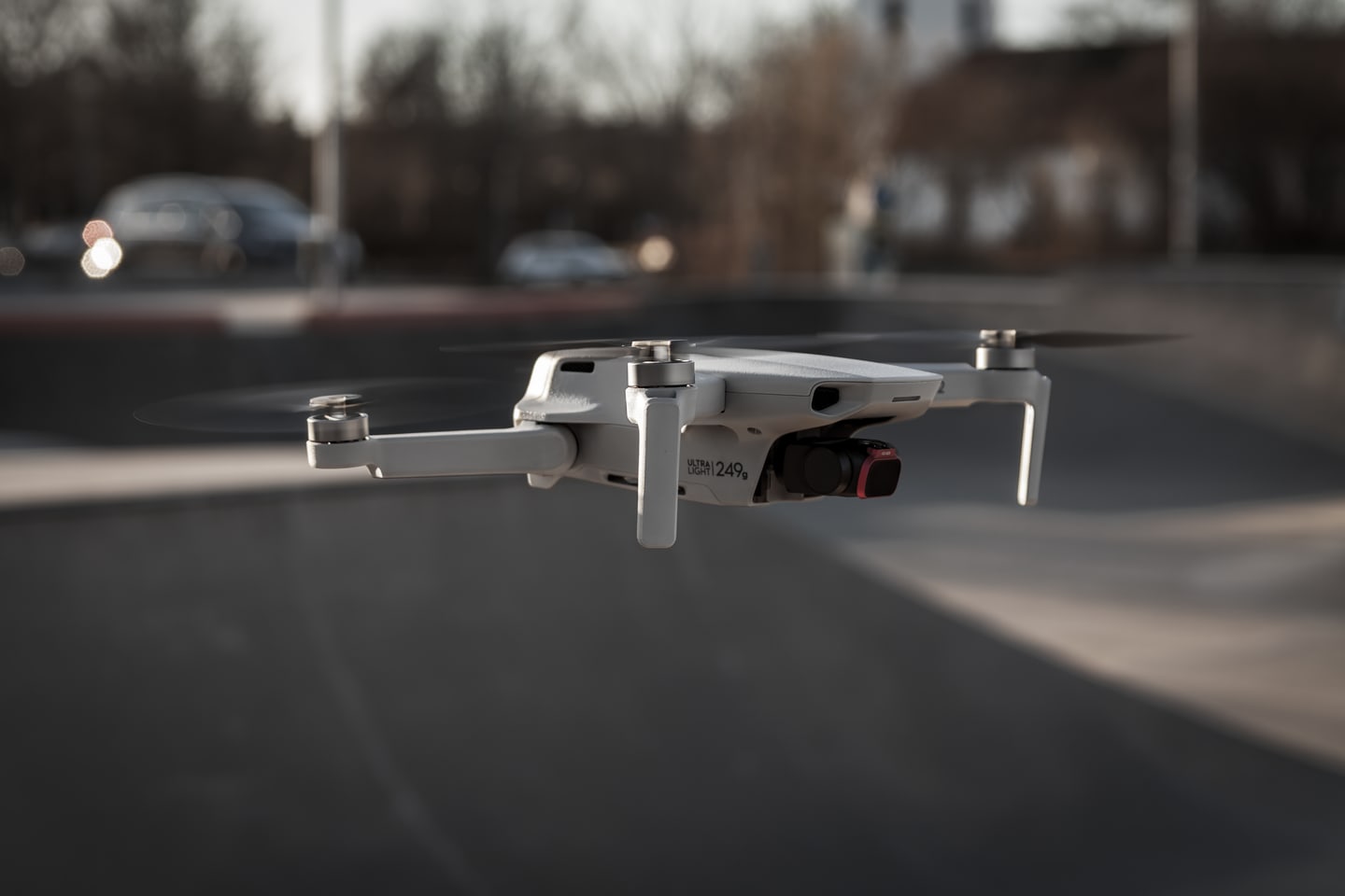 A DJI Mini 2 drone hovering low over a street.