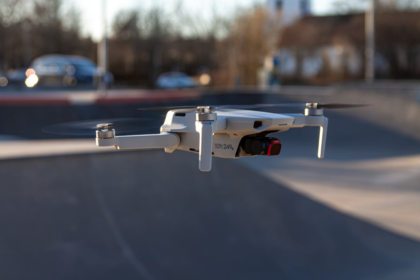 Close-up of a DJI Mini 2 drone hovering above pavement.