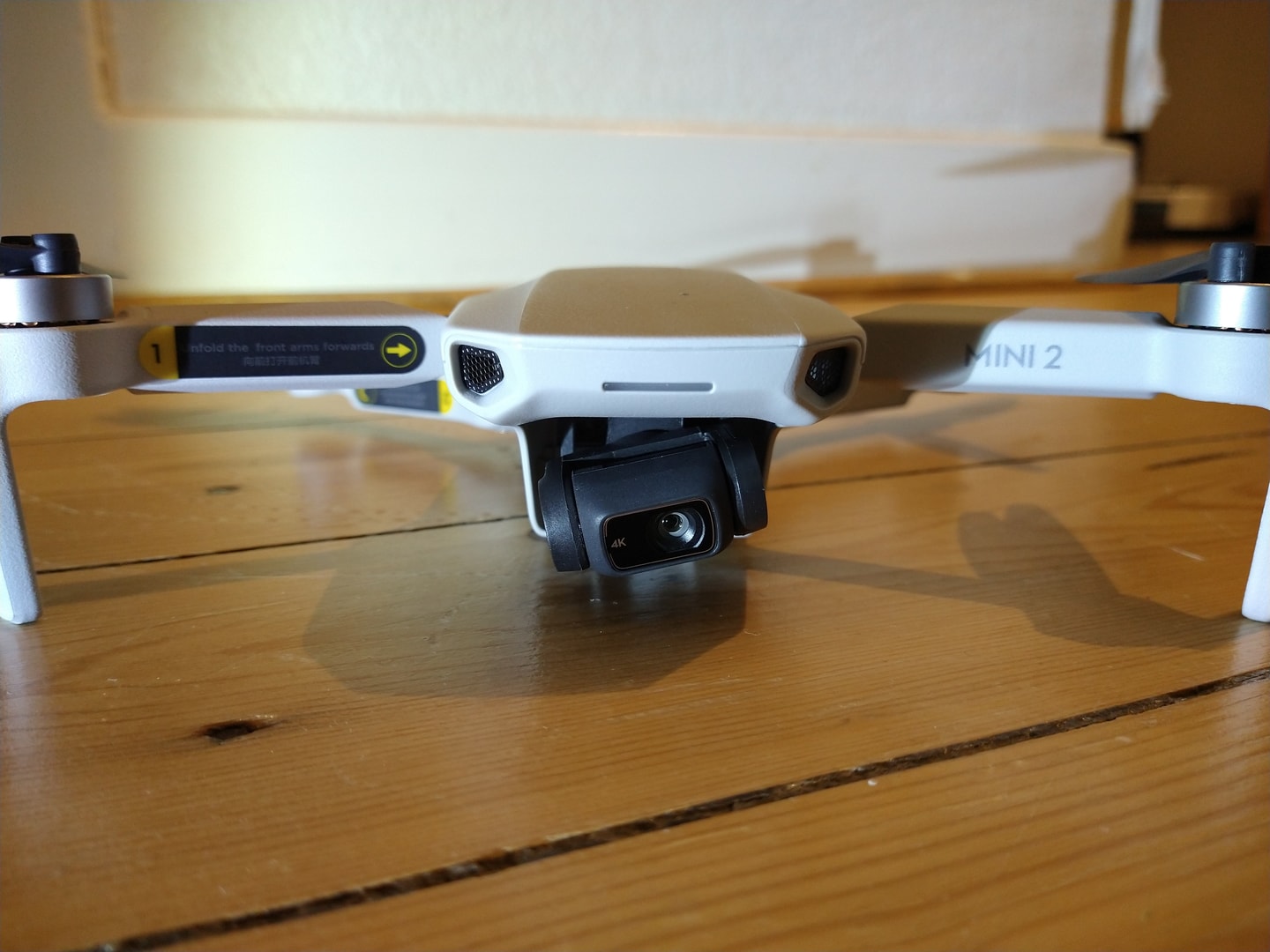 A DJI Mini 2 drone sits on a wooden table indoors.