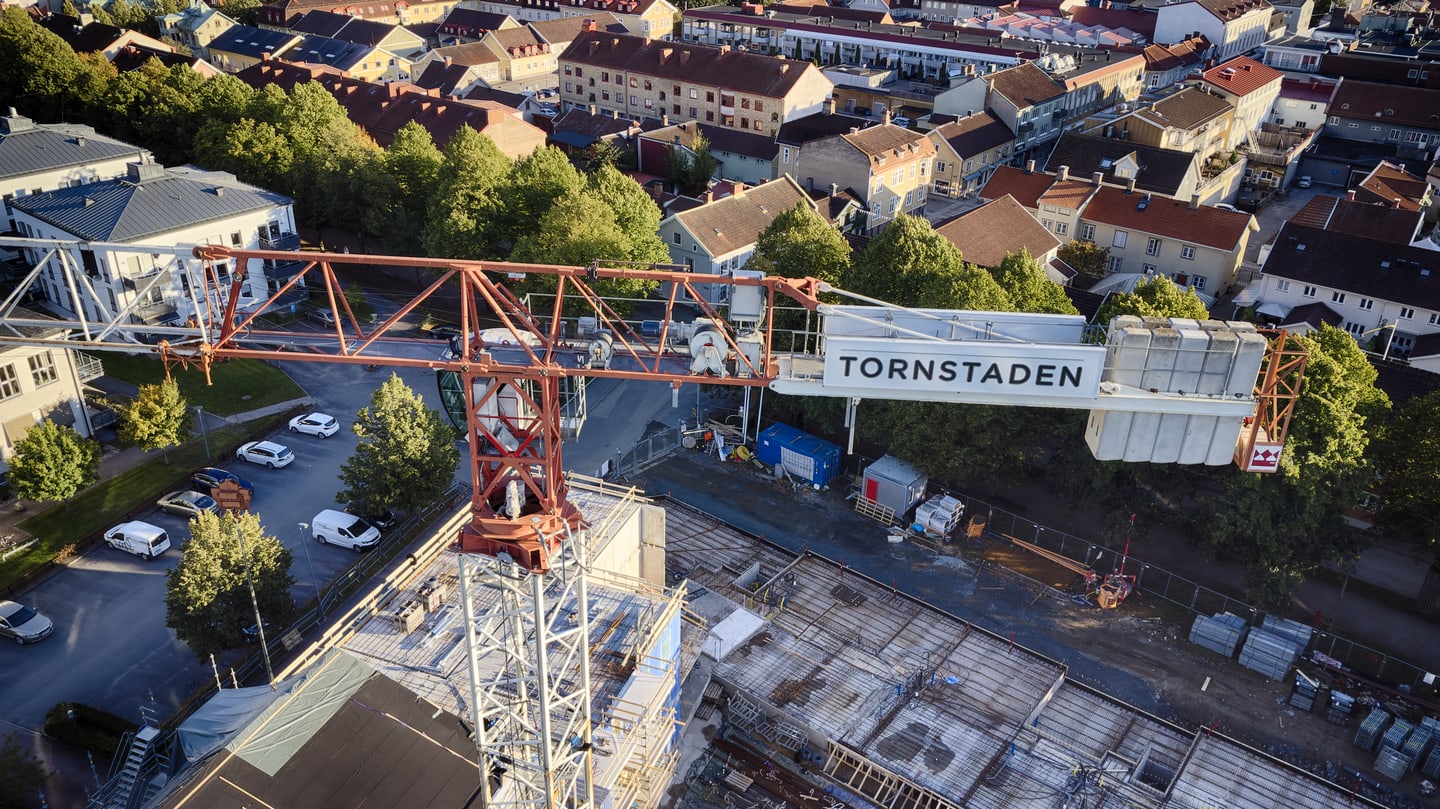 Aerial view over a town construction site with a large crane crossing the frame.